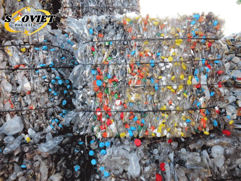 Các kiện phế liệu HDPE dạng can, thùng phuy màu xanh, trắng được xếp chồng lên nhau tại kho